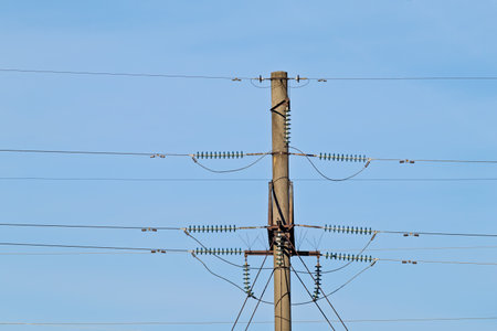 Urban utility pole with tangled power lines against a clear blue sky. Ideal for infrastructure, energy, or cityscape projects.の写真素材