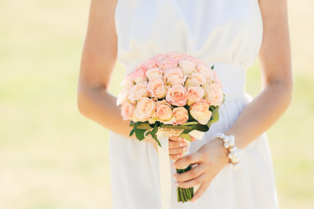 The bride in a white dress holds a bouquet of flowers. Close up. Wedding portrait, close-up photography. Summer weddingの写真素材