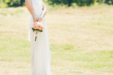 The bride in a white dress holds a bouquet of flowers. Close up. Wedding portrait, close-up photography. Summer weddingの写真素材