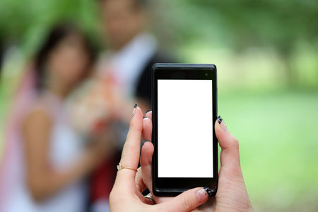 Close-up of a phone screen in the hands of a young woman. Hands holding cell phone with white blank display, blank screen for social media app advertisement. Mobile application technology conceptの写真素材