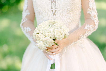The bride in a white dress holds a bouquet of flowers. Close up. Wedding portrait, close-up photography. Summer weddingの写真素材