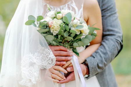 A close-up of a bride and groom holding a floral wedding bouquet together, highlighting love, unity, and romantic elegance.の写真素材