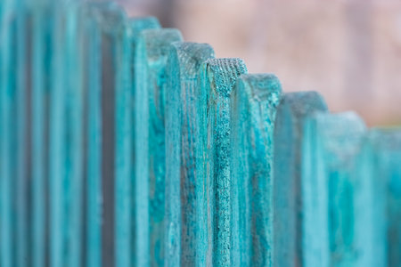 Close-up of weathered turquoise wooden fence with peeling paint. Macro shot of textured wood in soft focus. Rustic design and outdoor concept backgrounds and printsの写真素材