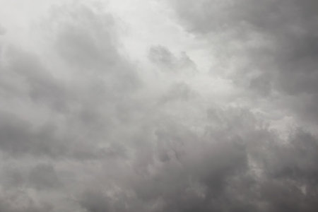 Dark, heavy storm clouds dominate the sky, creating a dramatic and moody atmosphere before an impending rainstorm.の写真素材