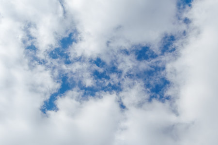 Soft white clouds scattered across a bright blue sky create a serene and peaceful atmosphere. Ideal for backgrounds or concepts of tranquility and natural beautyの写真素材