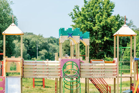 Brightly painted children's playground with slides, climbing elements, and towers in a sunny park...