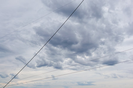 Overhead communication and internet cables stretch diagonally across a cloudy, stormy sky...