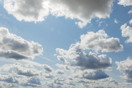 A scenic view of the sky filled with fluffy cumulus clouds of varying sizes against a backdrop of...