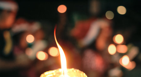 Bokeh of candle light and blurred carolers singing Christmas song in night of Christmas eveの写真素材