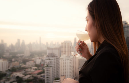 Elegant Asian woman drinking cocktail at rooftop barの写真素材