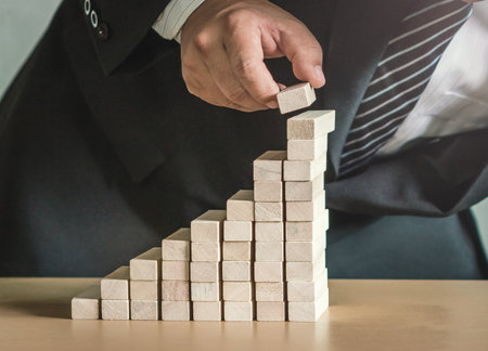 Deposit concept: Businessman adding a wood blockの写真素材