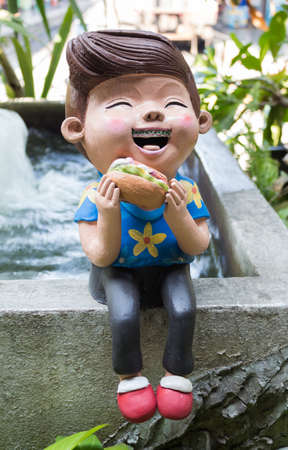 The Sculpture of happy smiling boy eat hotdog ceramicの写真素材
