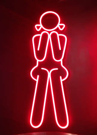 red neon sign for girl sitting in front of  female toiletsの写真素材
