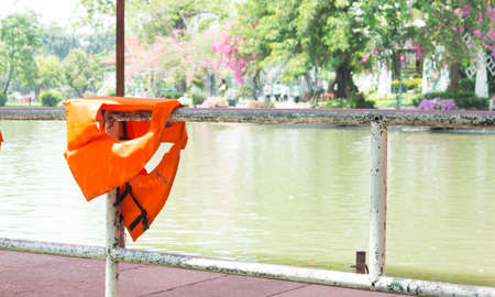 Orange life jackets dried on fenceの写真素材