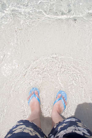 sea wave bubbles comes to feet walking on the beach, top-down view
