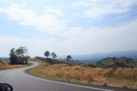 curve asphalt road with green meadow hillの写真素材