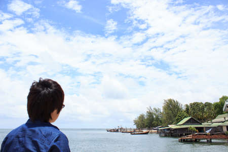 back of young man wear shirt jeans looking and thinking over sea backview