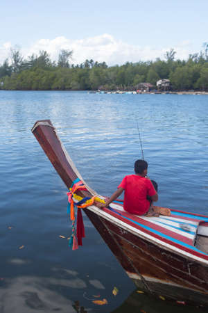 man angle fish on wooden boat in riverの写真素材