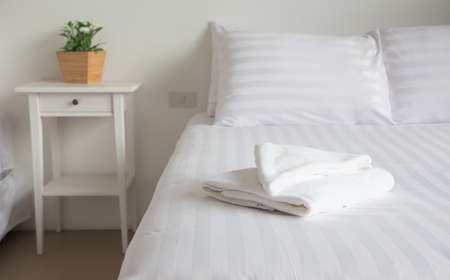 white king size bed, two pillows, towel and tree pot plant in bedroom for rest and relax, feel comfortableの写真素材
