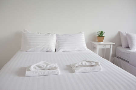 white king size bed, two pillows, towel and tree pot plant in bedroom for rest and relax, feel comfortableの写真素材