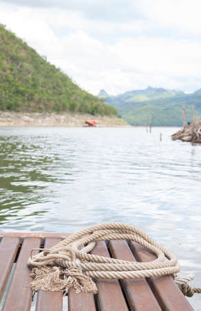 circle of ship rope on old wooden rafting in river backgroundの写真素材