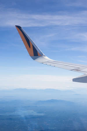 aerial view airplane wing and blue cloud sky, view through window glass above the clouds at sunset