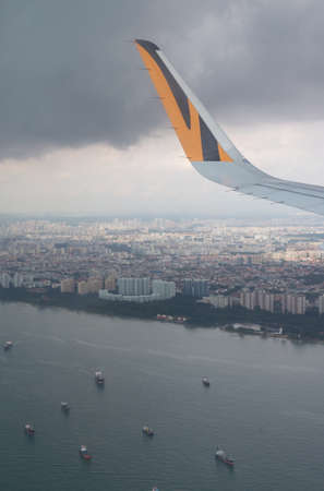 city view and cargo ships-floating sea and airplane wing, aerial view through window glassの写真素材