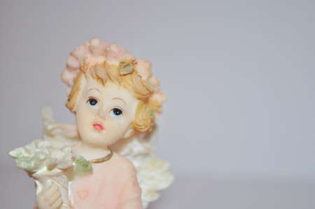 statue of a little gentle angel is holding flowers on a white backgroundの写真素材
