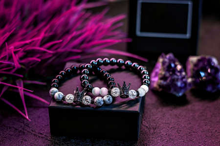Handmade bracelets made of natural stones on a packing box. Jewelry, on a purple background.の写真素材