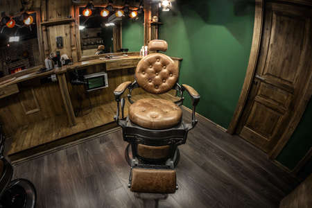 Vintage barbershop chair in the spotlight. Brown authentic interior with wood elements, tasteful designの写真素材