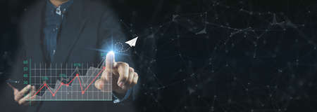 Businessman holding and showing a growing virtual hologram of statistics, graph and chart with arrow...