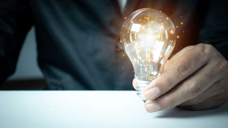 businessman hand holding light bulb with finance document and tool,concept of New ideas for business and fonance.の写真素材