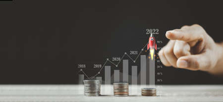 Businessperson pointing Flying Rocket Over Increasing Graph Of Coins