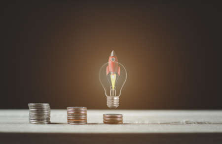 Light bulb rocket with coin ladder for financial plans or business ideas.の写真素材