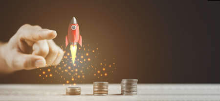 Businessperson pointing Flying Rocket Over Increasing Graph Of Coinsの写真素材