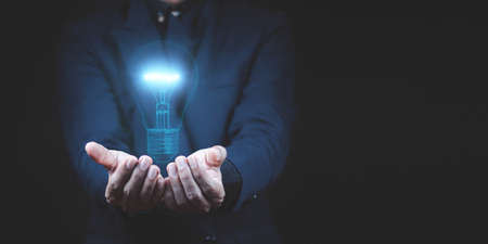businessman hand holding light bulb with finance document and tool,concept of New ideas for business and fonance.の写真素材