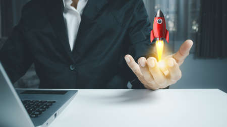 Male hand holding rocket icon that takes off,  rocket is launching and flying out, Business start up, Icon marketing on modern virtual interface.Start up conceptの写真素材