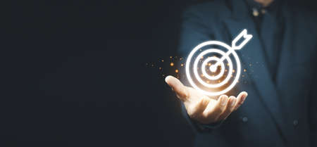 Businessman holding virtual dartboard and arrow with copy space for setup business objective target concept.の写真素材