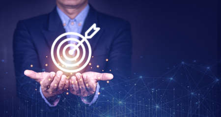 Businessman holding virtual dartboard and arrow with copy space for setup business objective target concept.の写真素材