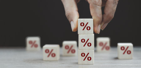 Interest rate financial and mortgage rates concept. Hand putting wood cube block increasing on top...