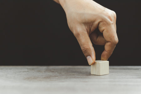 Hand arranging wood block stacking as step stair on wooden table. Business concept for growth success process. Copy spaceの写真素材