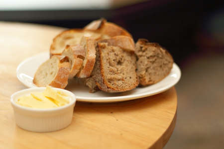 Loaf of walnut levain bread ,sliced bread on a dish served on a table with butterの写真素材