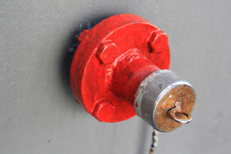 External fire hose equipment or Vintage Red Fire Hydrant on  Old Military Battleship grey wall