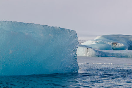 Large iceberg floating in icy waters with mountains