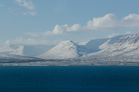 Snowy mountains with serene blue sea in foregroundの写真素材