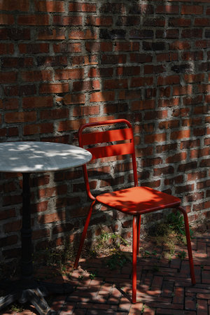 Outdoor cafÃ© setup with red chairs and a table against a brick wallの写真素材