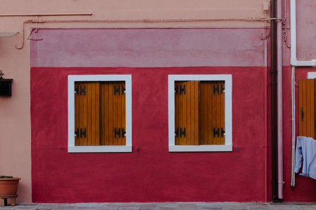 Vibrant red and pink building facade with wooden shuttersの写真素材