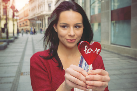 Girl with a lollipop in the shape of heart on the promenadeの写真素材