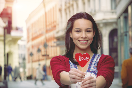 Girl with a lollipop in the shape of heart on the promenadeの写真素材