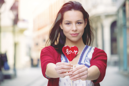 Girl with a lollipop in the shape of heart on the promenadeの写真素材